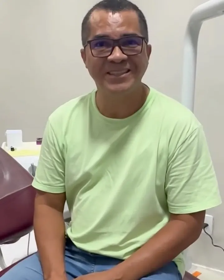 Paciente sentado na cadeira do consultório, sorrindo